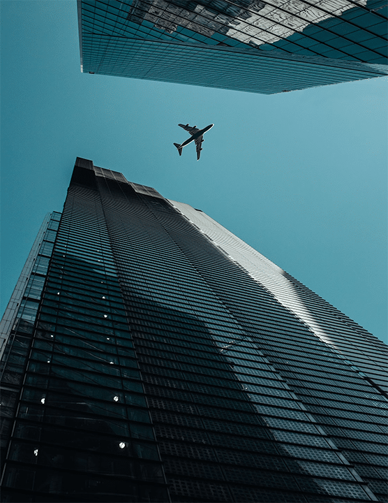 an airplane flying above large buildings